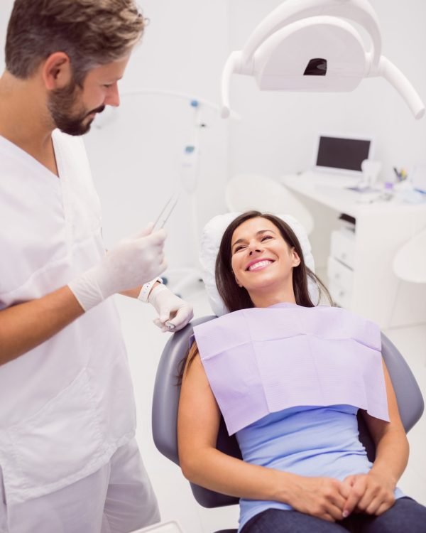 Dentist with smiling female patient in clinic