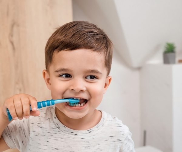 Child brushing teeth. Kids tooth brush and paste. Little funny baby boy brushing his teeth in modern bathroom on sunny morning. Dental hygiene and health for children.